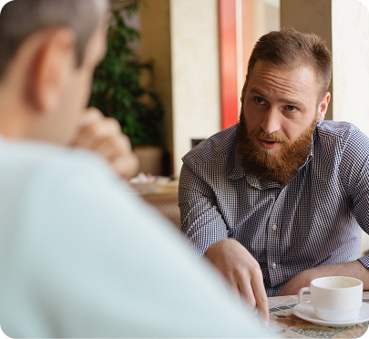 a person who is sitting at a table and talking with another person