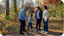 a group of three persons and a child walking in the forest