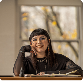 a young person who is sitting at the desk and smiles