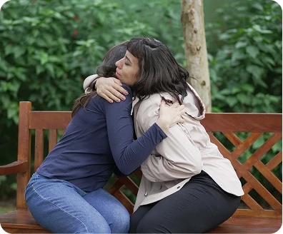 two persons hugging each other on the bench