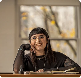 a young person who is sitting at the desk and smiling
